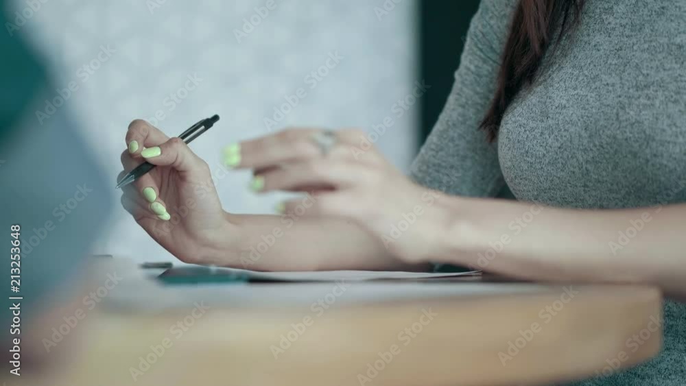 Close up european female hands with bright manicure thoughtfully holding pen paper on office desk creative business team meeting and brainstorming in modern start up office people group teamwork Close up european female hands with bright manicure thoughtfully holding pen paper on office desk creative business team meeting and brainstorming in modern start up office people group teamwork