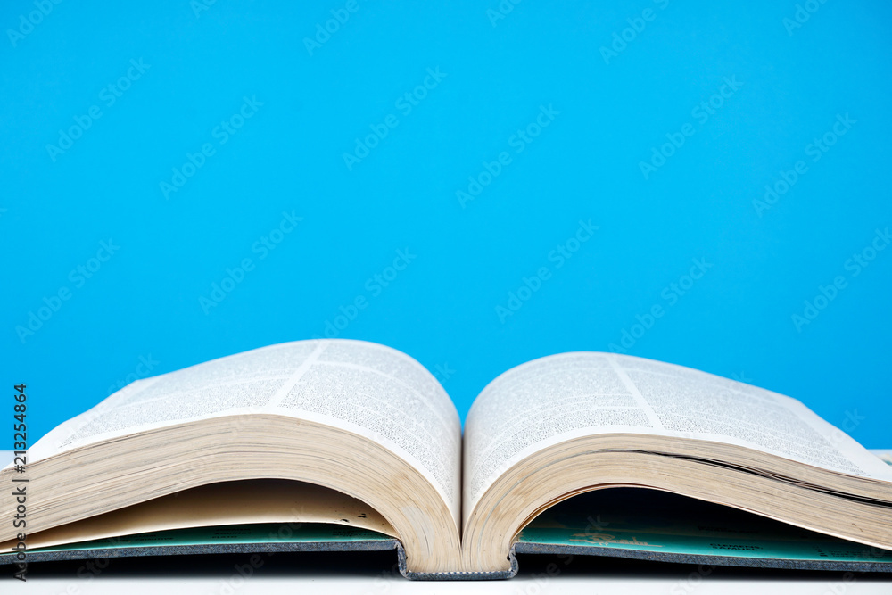 Education concept. An old book, eyeglasses over blue background Education concept. An old book, eyeglasses over blue background