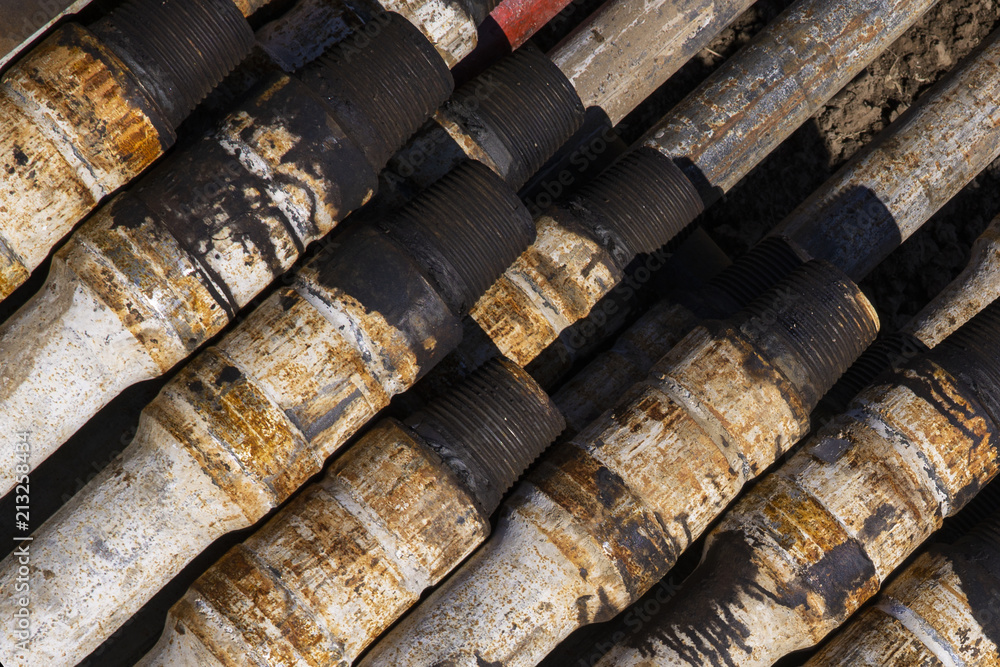 Fototapeta premium Oil Drill pipe. Rusty drill pipes were drilled in the well section. Downhole drilling rig. Laying the pipe on the deck. View of the shell of drill pipes laid in courtyard of the oil and gas warehouse.