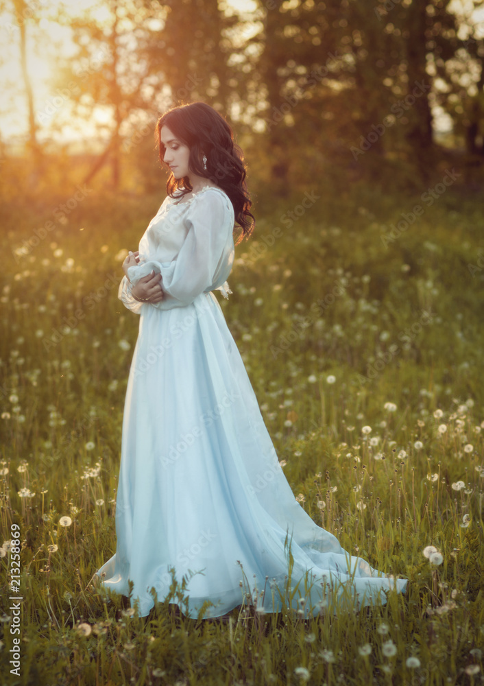 Girl in blue dress on a field of dandelions