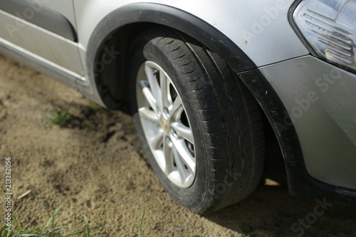 black wheel of a gray car on the sandy ground