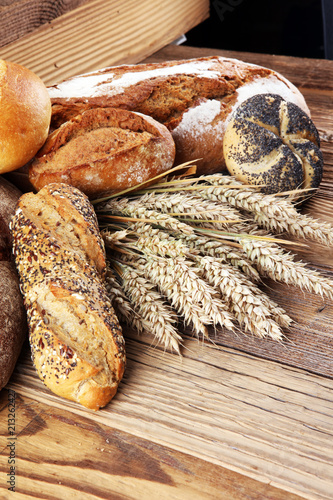 Different kinds of bread and bread rolls on board from above. Kitchen or bakery