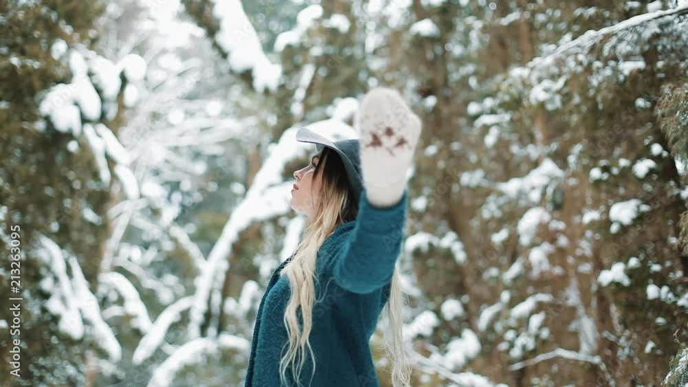 Lady in green coat and hat whirls around in the winter forest Lady in green coat and hat whirls around in the winter forest