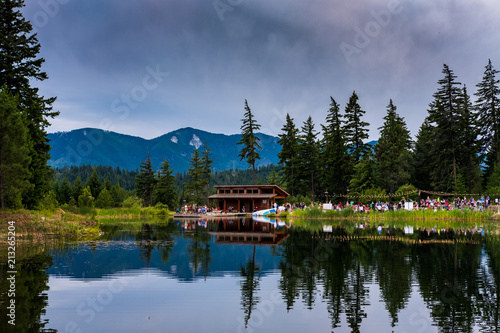 A party at a building on a lake with reflections and mountains in the background
