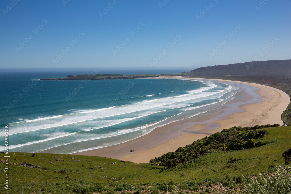 Stunning scenery on the southern coast of the south island, New Zealand. A 4WD can just be seen driving along the sand