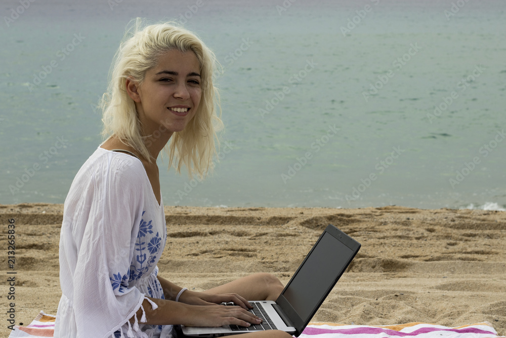 Relaxed woman typing on a laptop on the beach