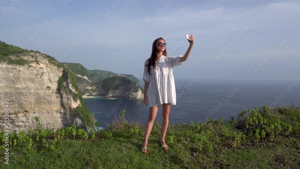 Woman making selfie on Kelingking beach background at Nusa Penida island. Woman making selfie on Kelingking beach background at Nusa Penida island.