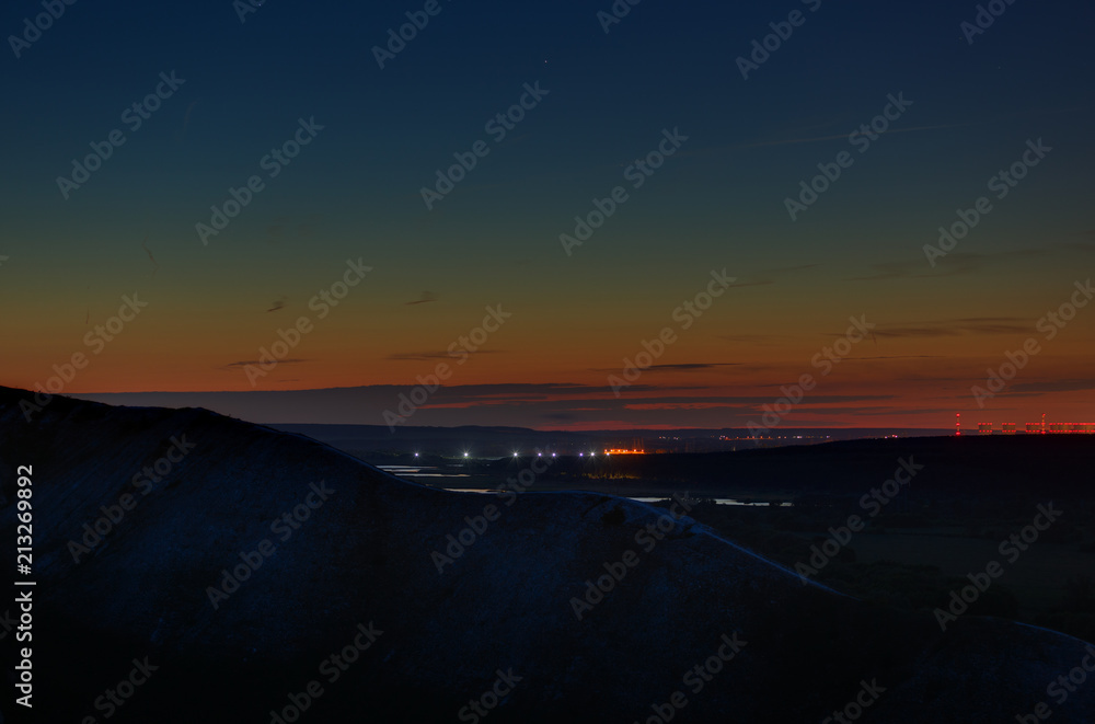 Stars of outer space in the night sky over the river valley. Landscape in the twilight on long exposure.
