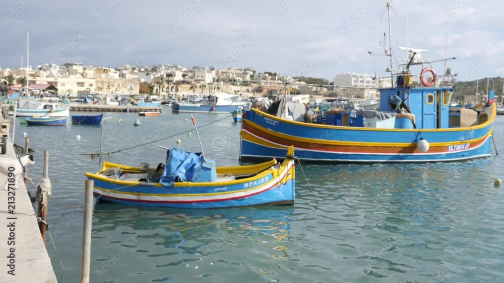 Marsaxlokk, Malta - beautiful fishing village architecture with colored boatsat at anchor in a bay Marsaxlokk, Malta - beautiful fishing village architecture with colored boatsat at anchor in a bay