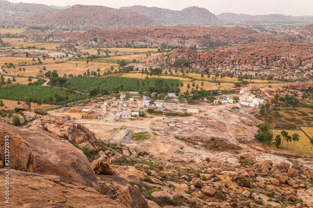 Rice fields in the village of Hampi, India. Palm trees, sun,rice fields, large stones in Hampi. Tropical exotic landscape. Beautiful valley. View from high hill. Rice fields in the village of Hampi, India. Palm trees, sun,rice fields, large stones in Hampi. Tropical exotic landscape. Beautiful valley. View from high hill.