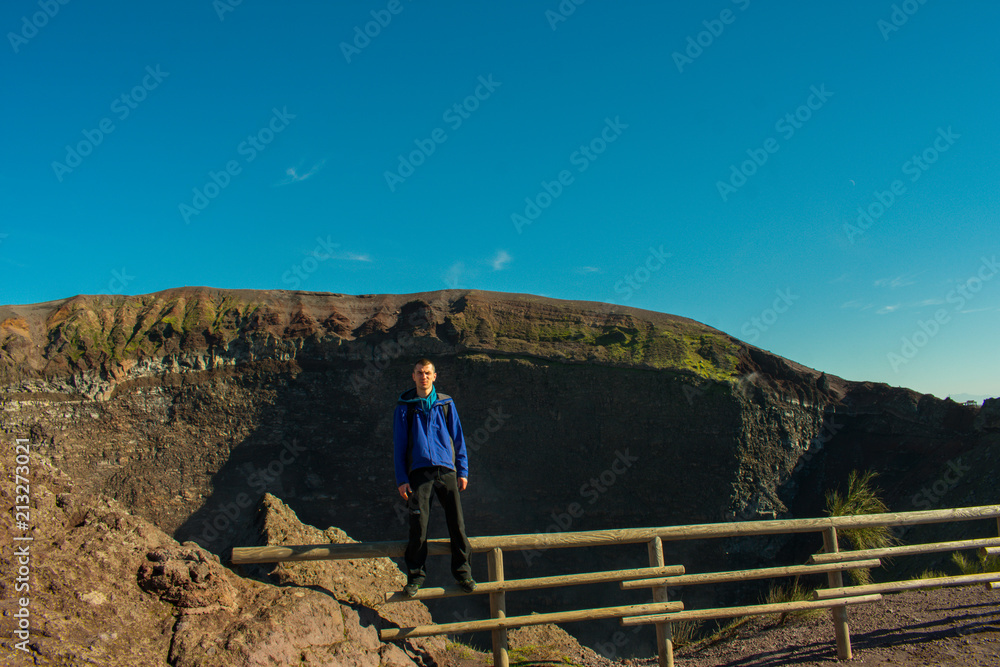 Young man standing on top of Vesuvius volcano crater next to Naples in a summer day, famous and popular place for tourists in Italy Young man standing on top of Vesuvius volcano crater next to Naples in a summer day, famous and popular place for tourists in Italy