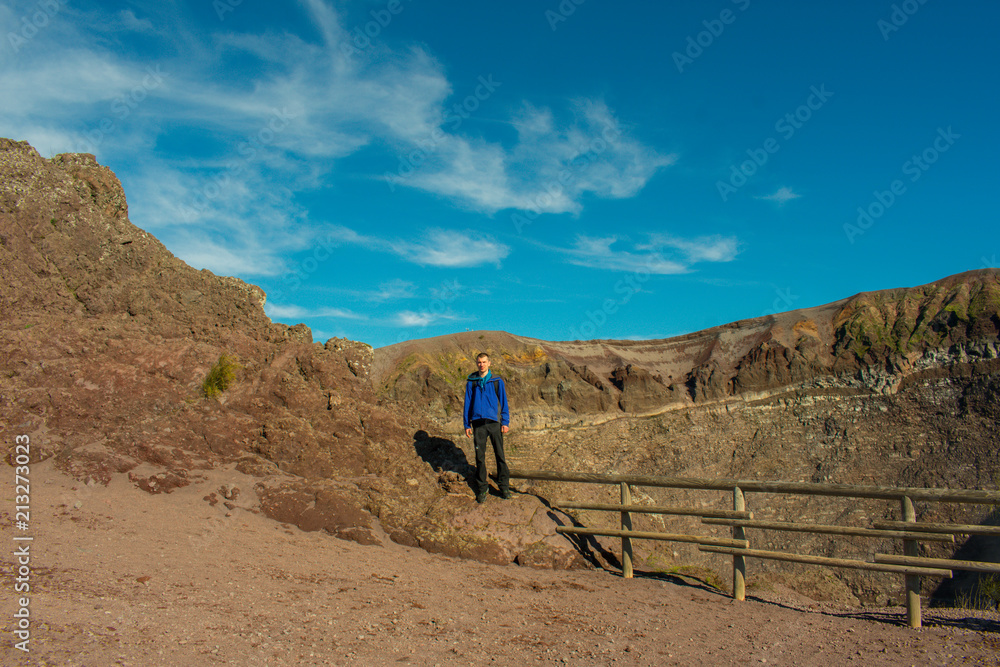 Young man standing on top of Vesuvius volcano crater next to Naples in a summer day, famous and popular place for tourists in Italy