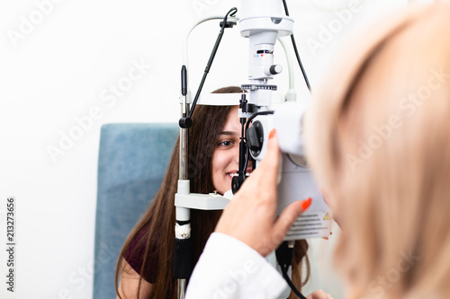 Optometrist checking young and beautiful patient vision at eye clinic. Medical examination.