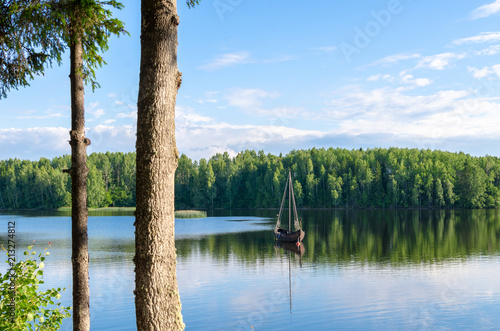 View of a peaceful forest lake with an anchored boat in summer. Photo taken at Paunküla Reservoir in Estonia photo