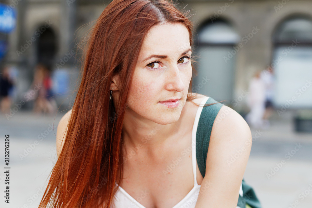 Young beautiful redhead woman sitting  on bench and looking