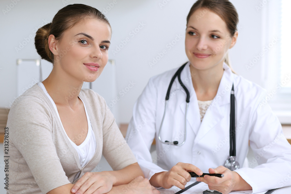 Doctor and patient having a pleasure talk while sitting at the desk at hospital office. Healthcare and medicine concept Doctor and patient having a pleasure talk while sitting at the desk at hospital office. Healthcare and medicine concept