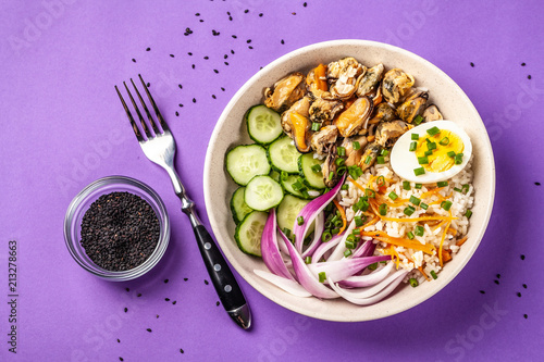 Hawaiian Pake salad with mussels, boiled egg, red onion, cucumber and rice, with black sesame. in a gray plate. On a purple colored trendy background in 2018. copy space, top view photo