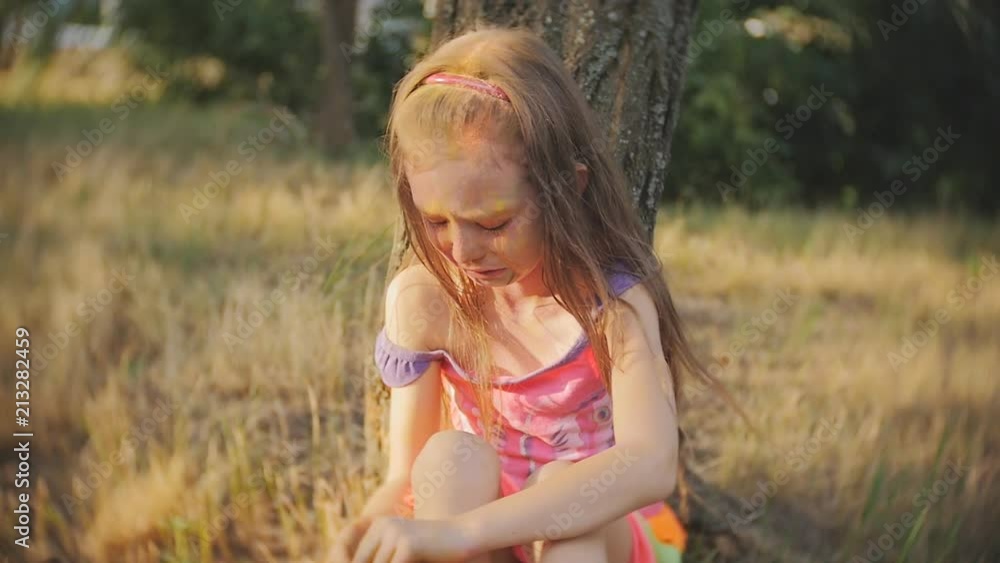 Little girl crying sitting in a tree on the festival of colors Holi Little girl crying sitting in a tree on the festival of colors Holi