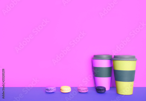 Cup of coffee to go with macaron on yellow and pink background