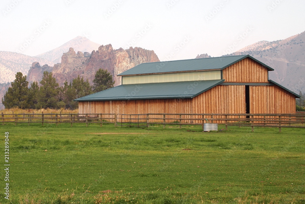 A large barn in a pasture in rural Central Oregon with Smith Rocks in the fog in the background on a fall day. A large barn in a pasture in rural Central Oregon with Smith Rocks in the fog in the background on a fall day.