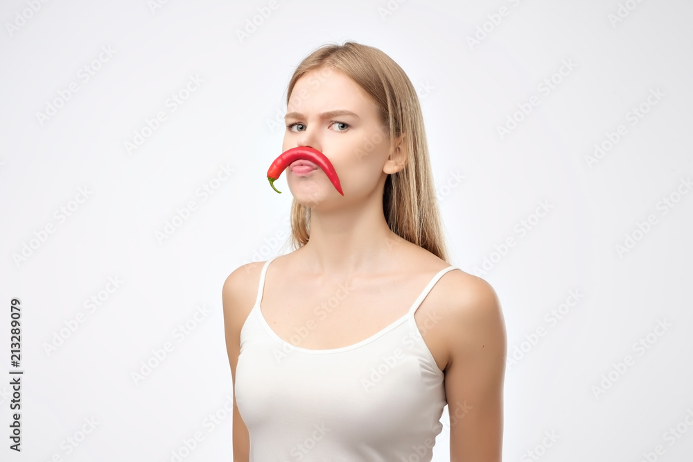 European young woman holding red hot chili pepper like mustache European young woman holding red hot chili pepper like mustache