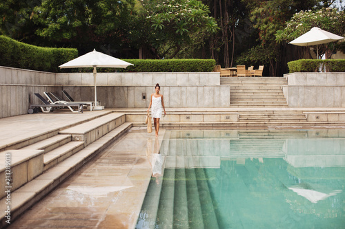 Woman in white dress near swimming pool