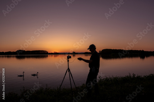 Silhouette von einem Fotografen und Schwan beim Sonnenuntergang am Rhein Iffezheim