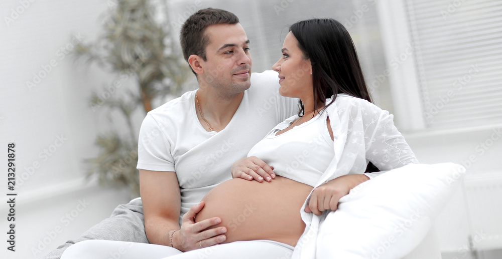 husband and pregnant wife lying on the bed in the bedroom. husband and pregnant wife lying on the bed in the bedroom.
