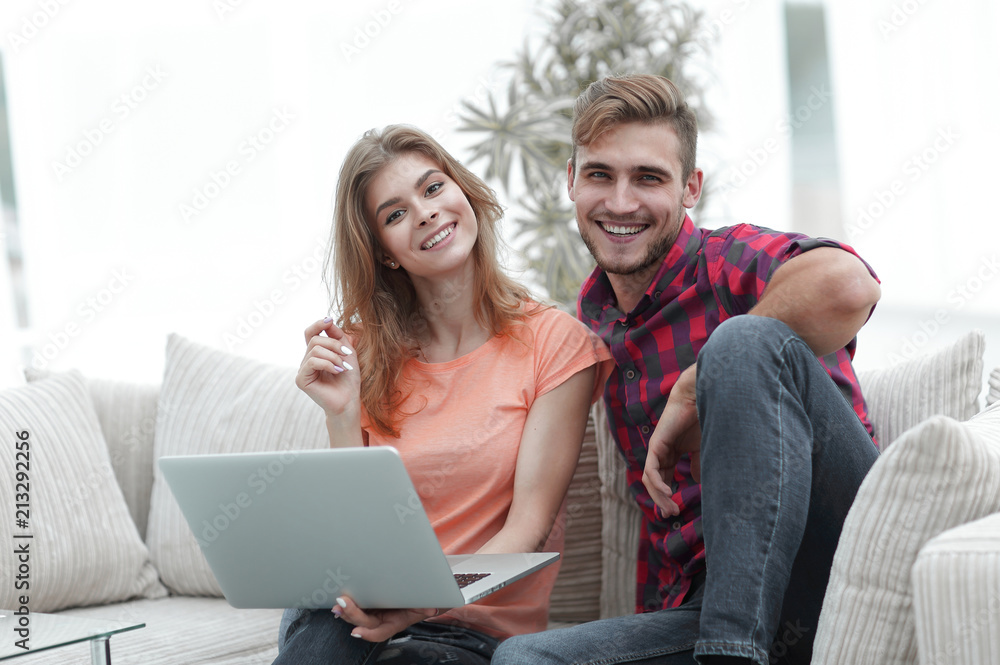 young couple of students with laptop sitting on the couch young couple of students with laptop sitting on the couch