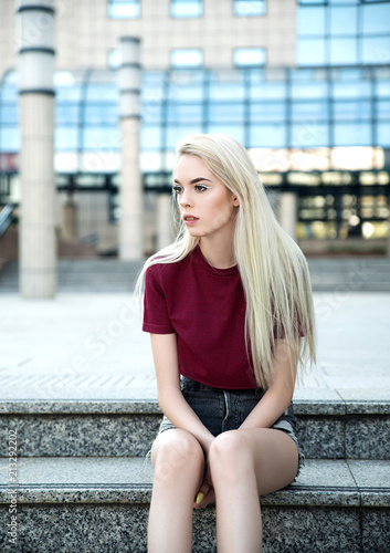 Young blonde woman sitting outdoors