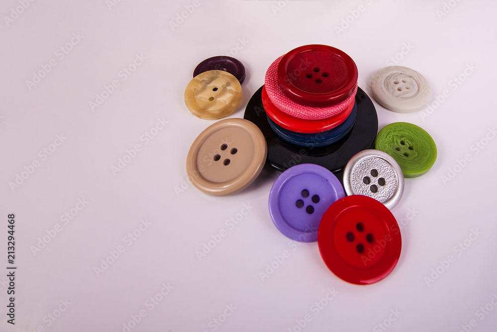 Clothing shirt sewing buttons stacked piled up and scattered multi colors on solid background Clothing shirt sewing buttons stacked piled up and scattered multi colors on solid background