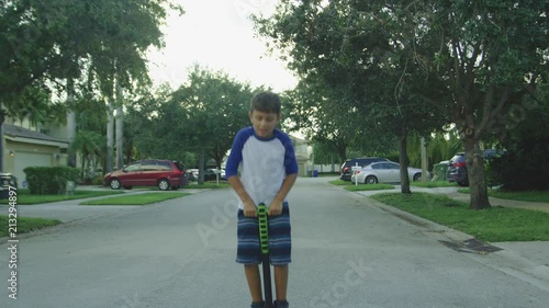 Slow motion of boy bouncing on a pogo stick while smiling and looking at camera photo