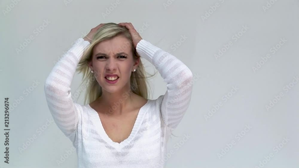Screaming angry young woman holding her head between hands. Screaming angry young woman holding her head between hands.