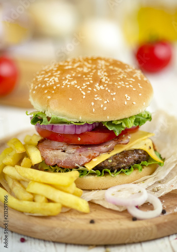 Delicious hamburger on wooden table with ingredients 