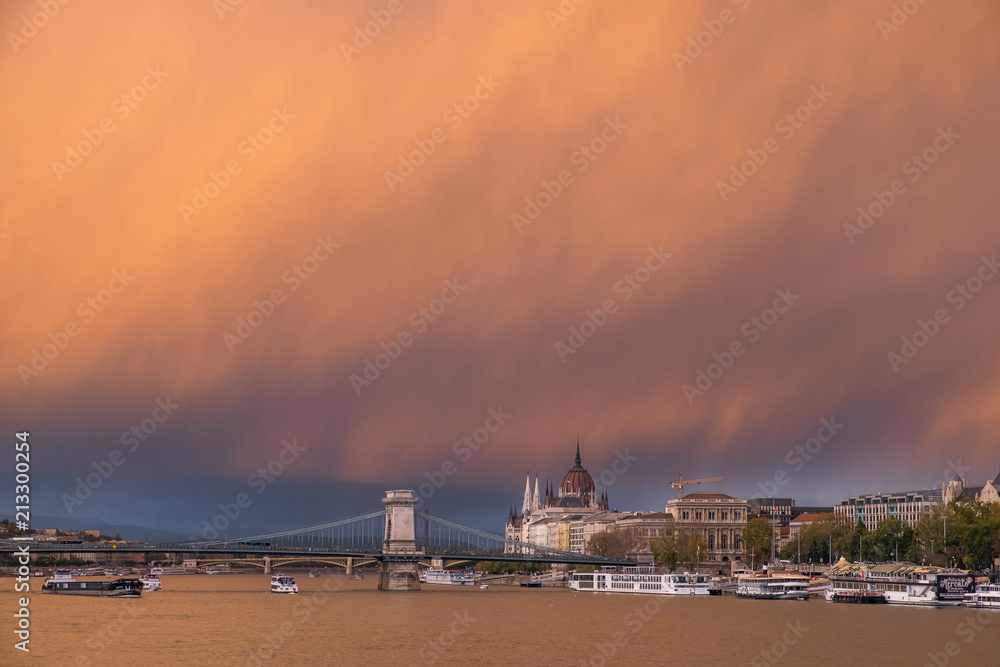 Orange sky in Budapest after rain with a snuff from the Buda side. On the Pesti quay you can see the hotel chain and Parliament with the Chain Bridge.