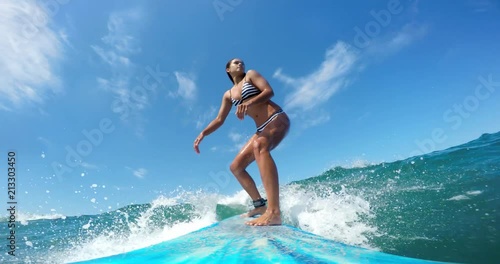 POV girl surfing riding ocean wave on sunny day  photo