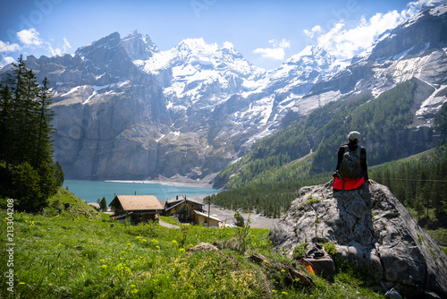 A hiker/travellers enjoys the beauty of Oeschinensee with An snow alpine as a background