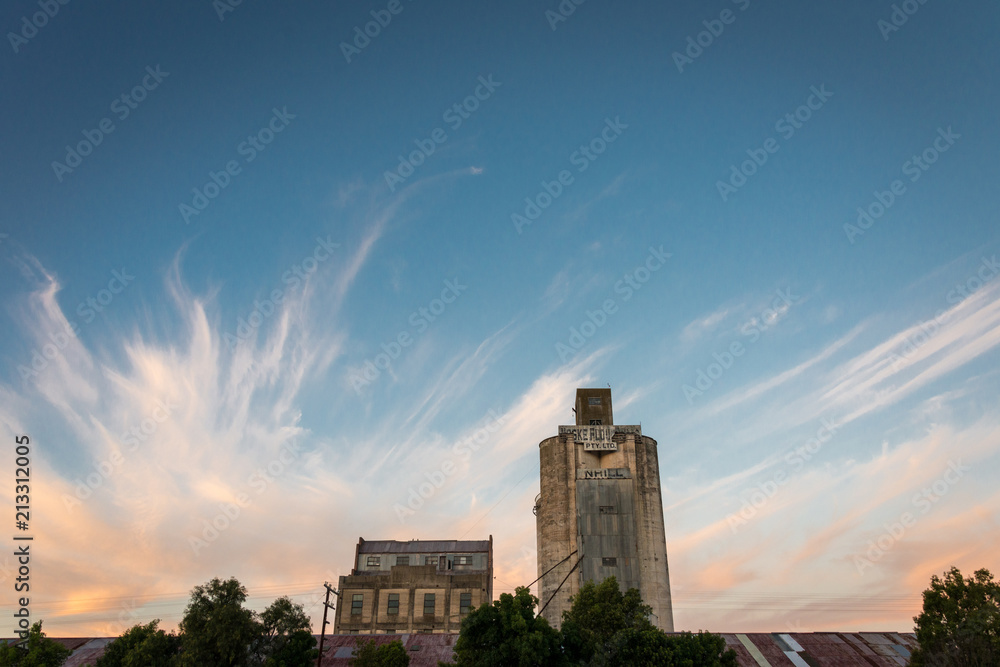 An old grain silo and buildings against a dramatic sunset sky in Nhill, Victoria Australia An old grain silo and buildings against a dramatic sunset sky in Nhill, Victoria Australia