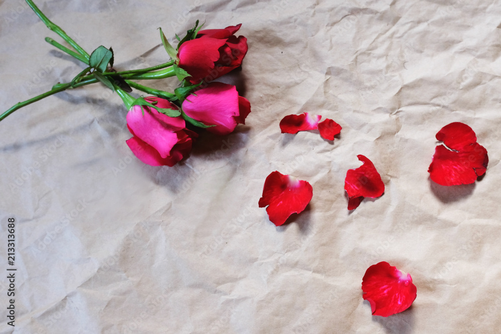 Red roses and petals on brown crumpled paper background, Top view.Valentine's day holiday concept. Copy space