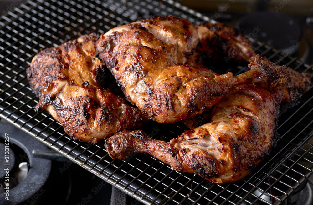 A stack of grilled tandoori spiced chicken legs on a wire rack.