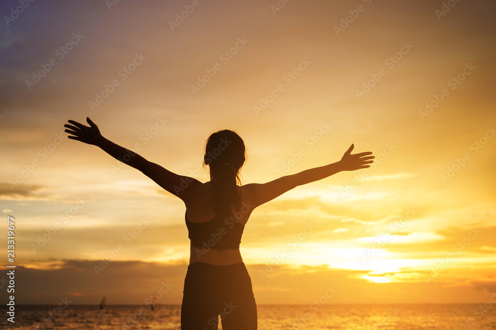 happy young woman enjoying freedom with open hands at sunset. young woman christian worship concept.