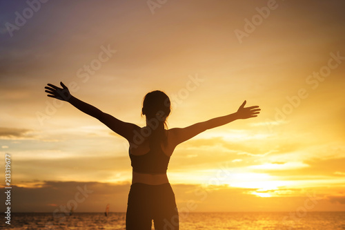 happy young woman enjoying freedom with open hands at sunset. young woman christian worship concept.