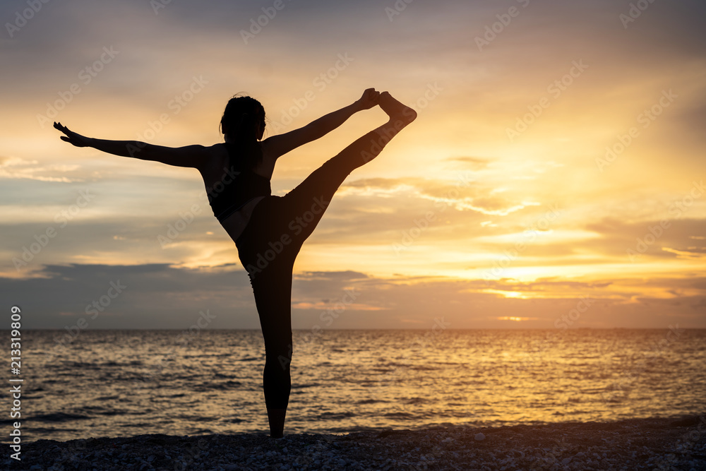 Young healthy woman practicing yoga on the beach exercise at sunset time. healthy concept.