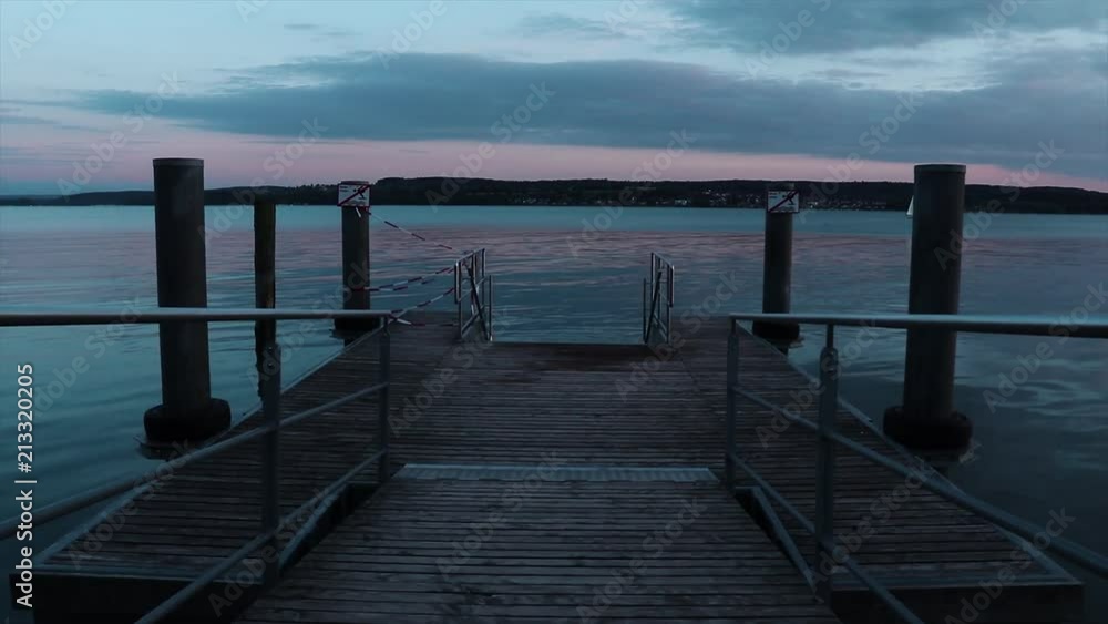The camera is moving along a berth during sunset. The sunset gives beautiful reflections on the calm surface of Lake Constance. The camera is moving along a berth during sunset. The sunset gives beautiful reflections on the calm surface of Lake Constance.
