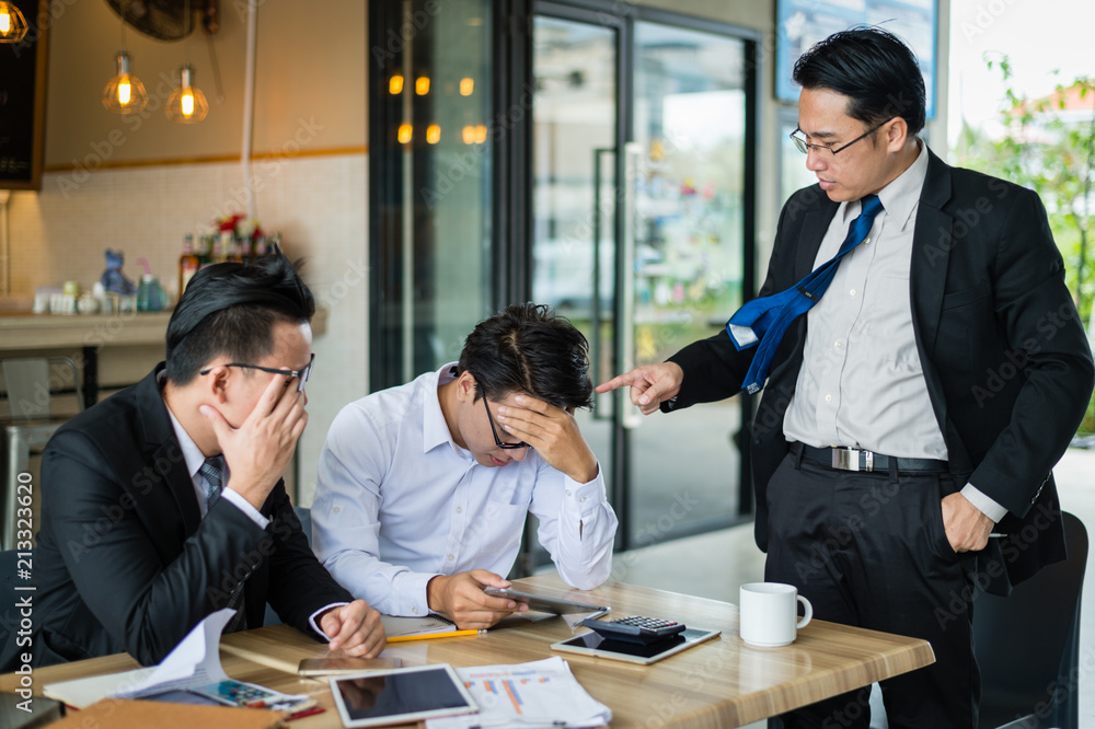 Fototapeta premium businessman pointing his finger to employee because he is very angry for reported sales decrease. employee is very stressed and using hand hold head.