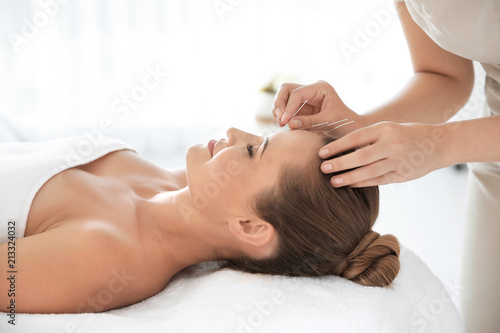 Young woman undergoing acupuncture treatment in salon photo