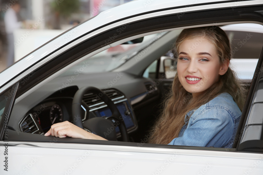 Young woman sitting on driver's seat of car