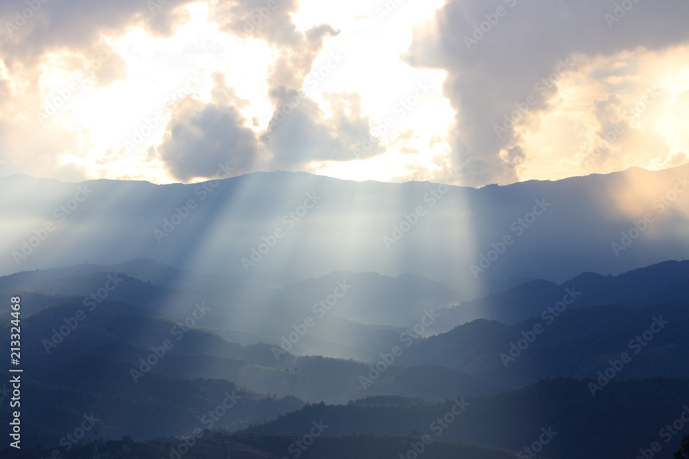 Dramatic god lights passing through clouds and shining on mountain ranges. warm light shower. God hope and dream concept