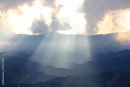 Dramatic god lights passing through clouds and shining on mountain ranges. warm light shower. God hope and dream concept