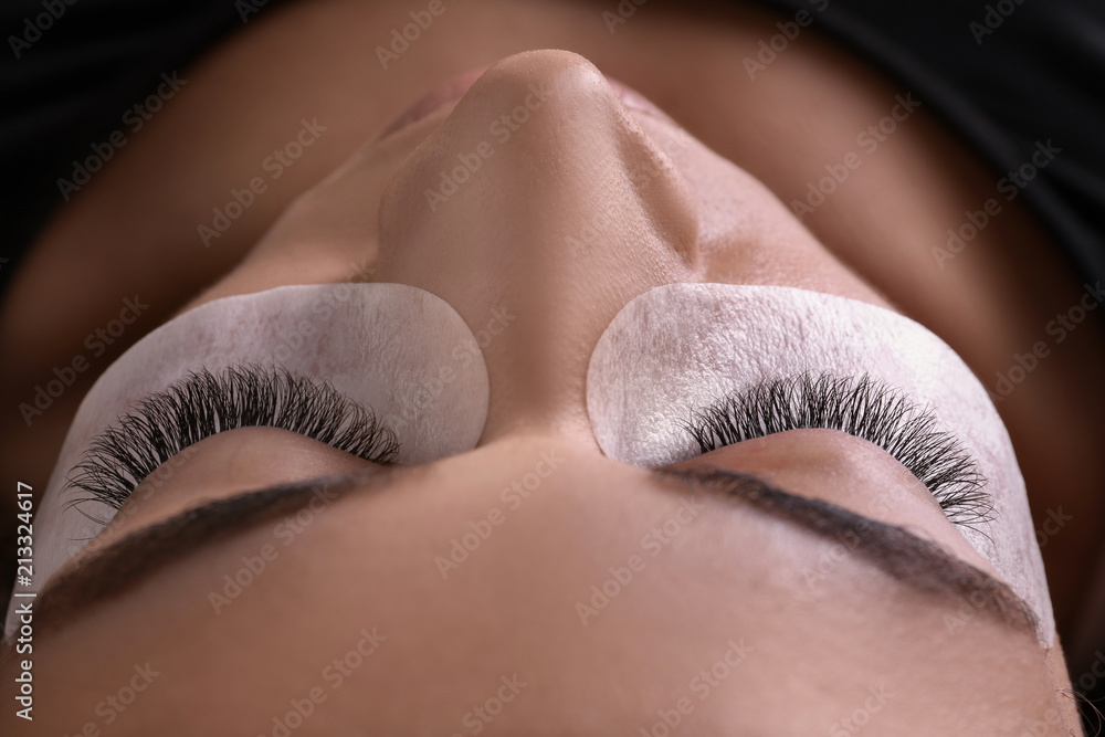 Naklejka premium Młoda kobieta przechodzi procedurę przedłużania rzęs, zbliżenie